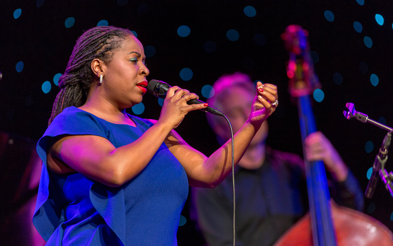 Johnaye Kendrick singing with left arm extended