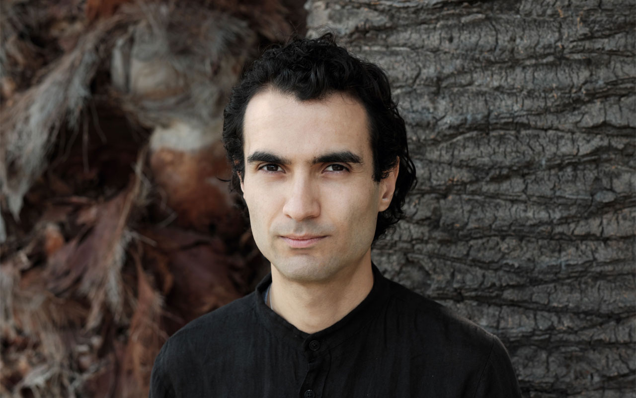Tigran Hamasyan standing in front of a tree