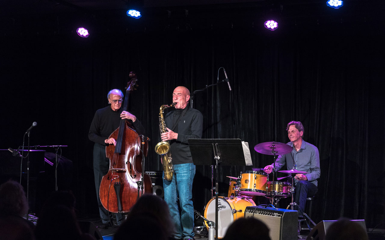 Jeff Johnson, Rick Mandyck and John Bishop playing bass, saxophone, and drums.