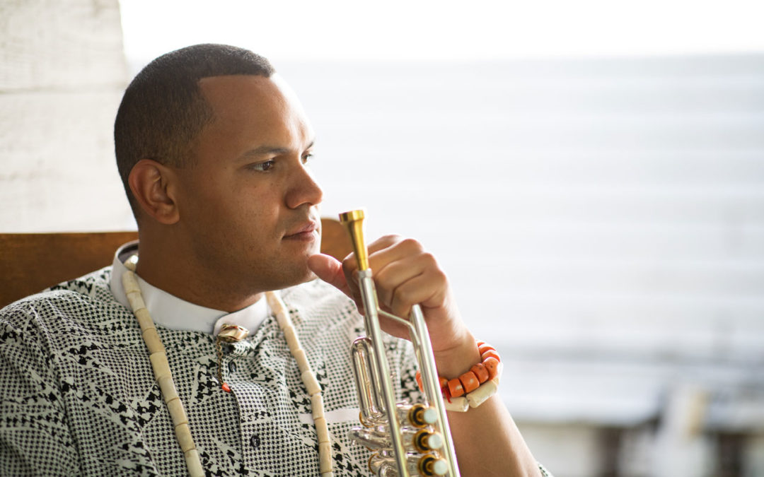 Ahamefule J. Oluo sitting holding a trumpet