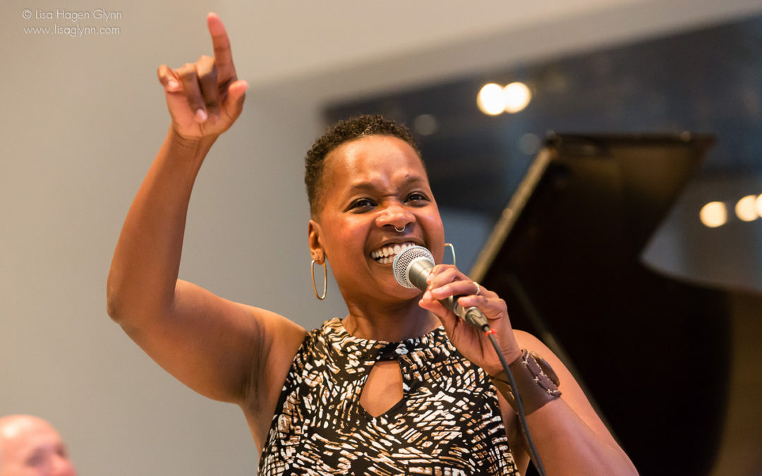 LaVon Hardison smiling and singing with her arm held in the air with enthusiasm.