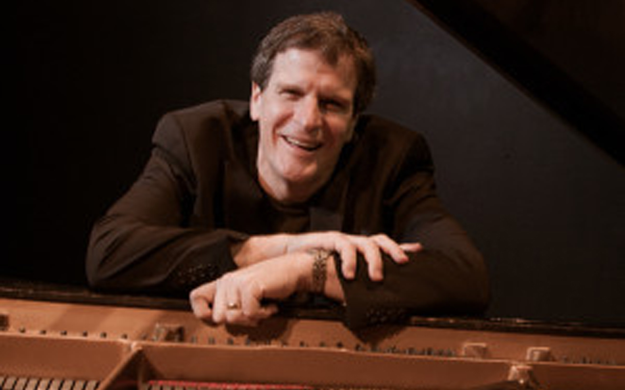 Randy Halberstadt smiling and leaning on the piano