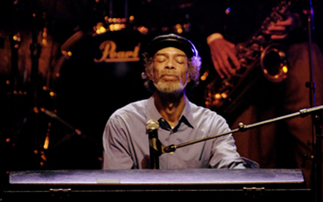 Gil Scott Heron playing the keyboard, with his head raised and eyes closed.