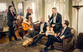 Hot Club of San Fransisco in a living room with their instruments.